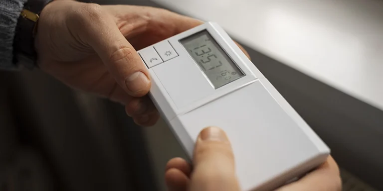 water heater - What is the Right Temperature for My Water Heater? - person holding water heater remote control