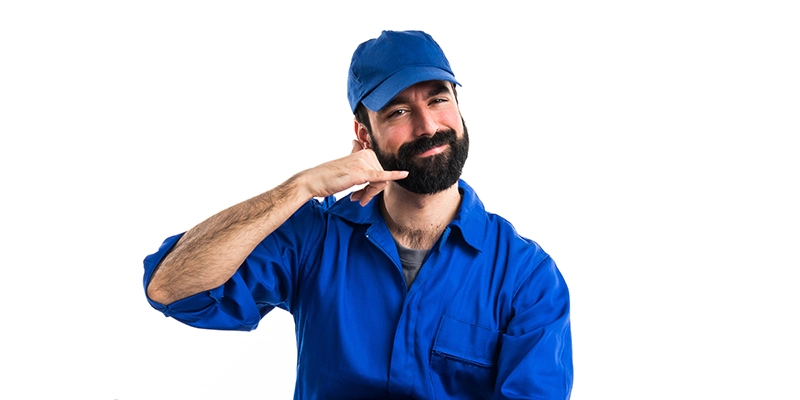 quality plumbing company - 5 Tips to Hiring a Quality Plumbing Company - man in blue overalls making phone gesture