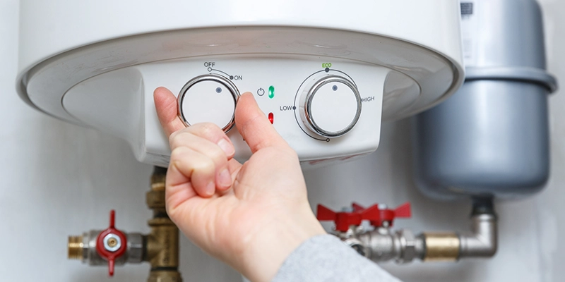 water heater - Extending the Life of Your Water Heater - person adjusting dial on wall mounted water heater