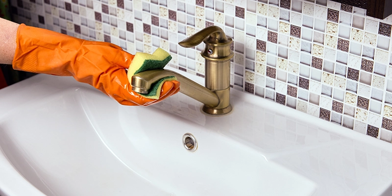 removing limescale - Removing and Preventing Limescale - person cleaning brass color faucet