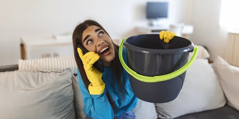 plumbing problems - Simple Things You Can Do to Prevent Plumbing Problems this Spring - woman holding bucket in living room on the phone