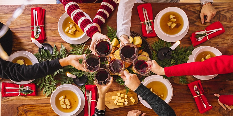 plumbing - Pain in the Drain: How the Holidays Can Affect Your Plumbing - top view of christmas dinner people toasting