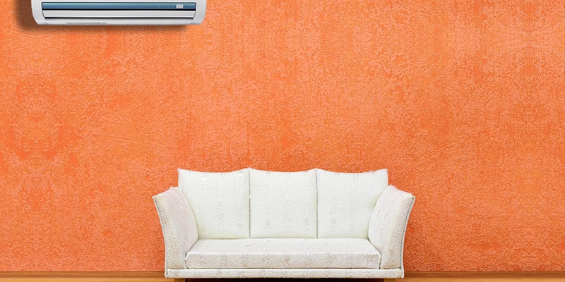 ductless - Mini Splits Indoor Unit - room with orange wall white couch and air conditioner on wall