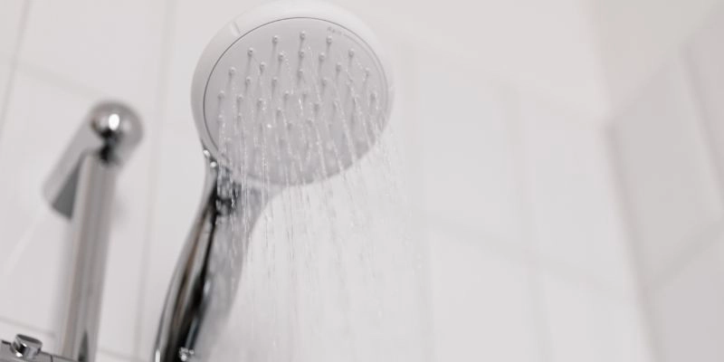increase water pressure - Six Tips to Increase Water Pressure in Your Shower - white shower head on white tile background